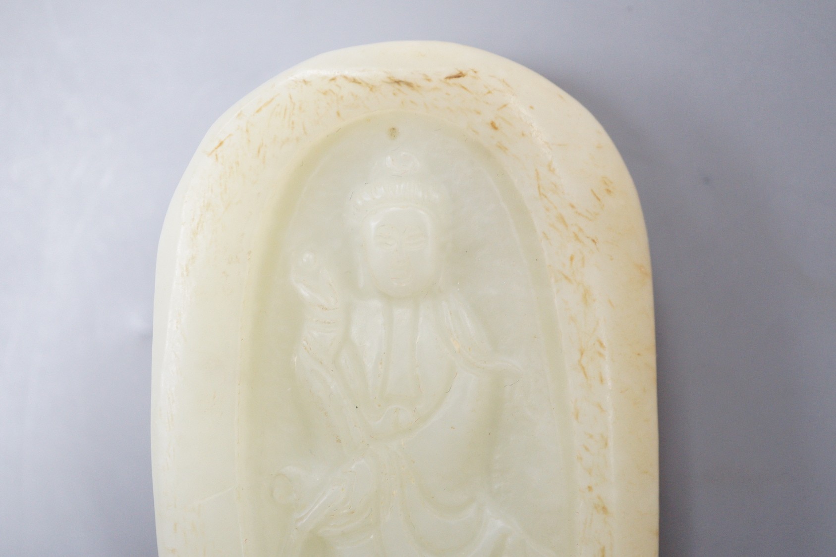 A Chinese celadon jade pebble carving depicting Guanyin, 7.5cm tall